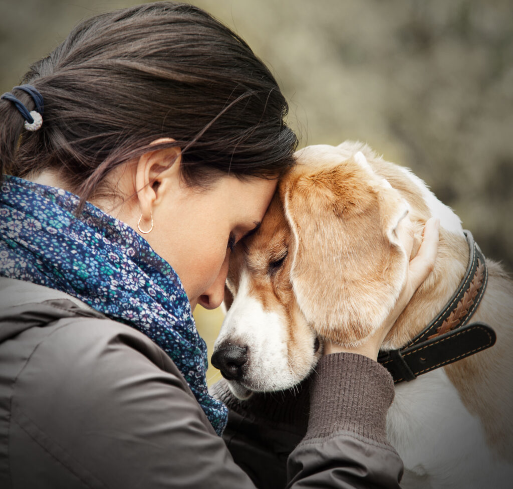 Woman resting her head against a beagle's head