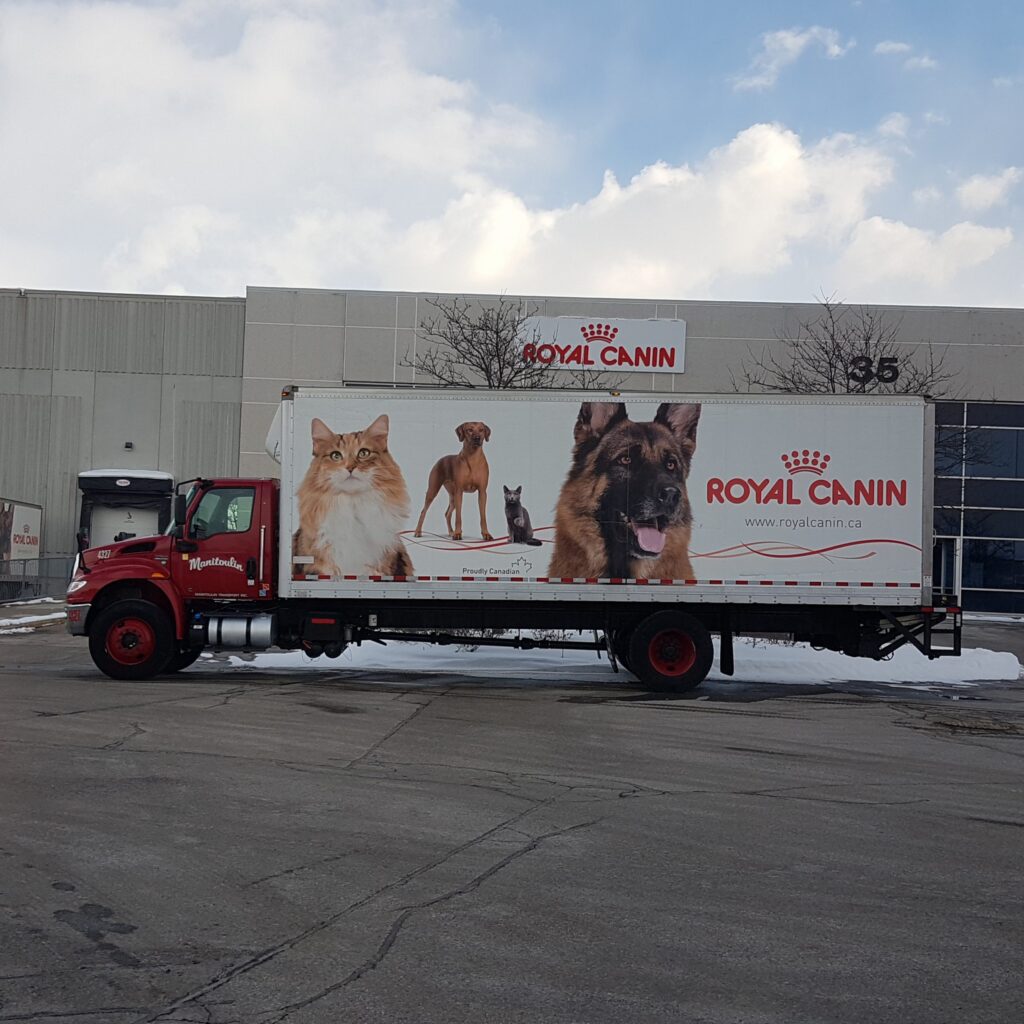 Royal Canin delivery truck with pet photos on its side, parked outside a building