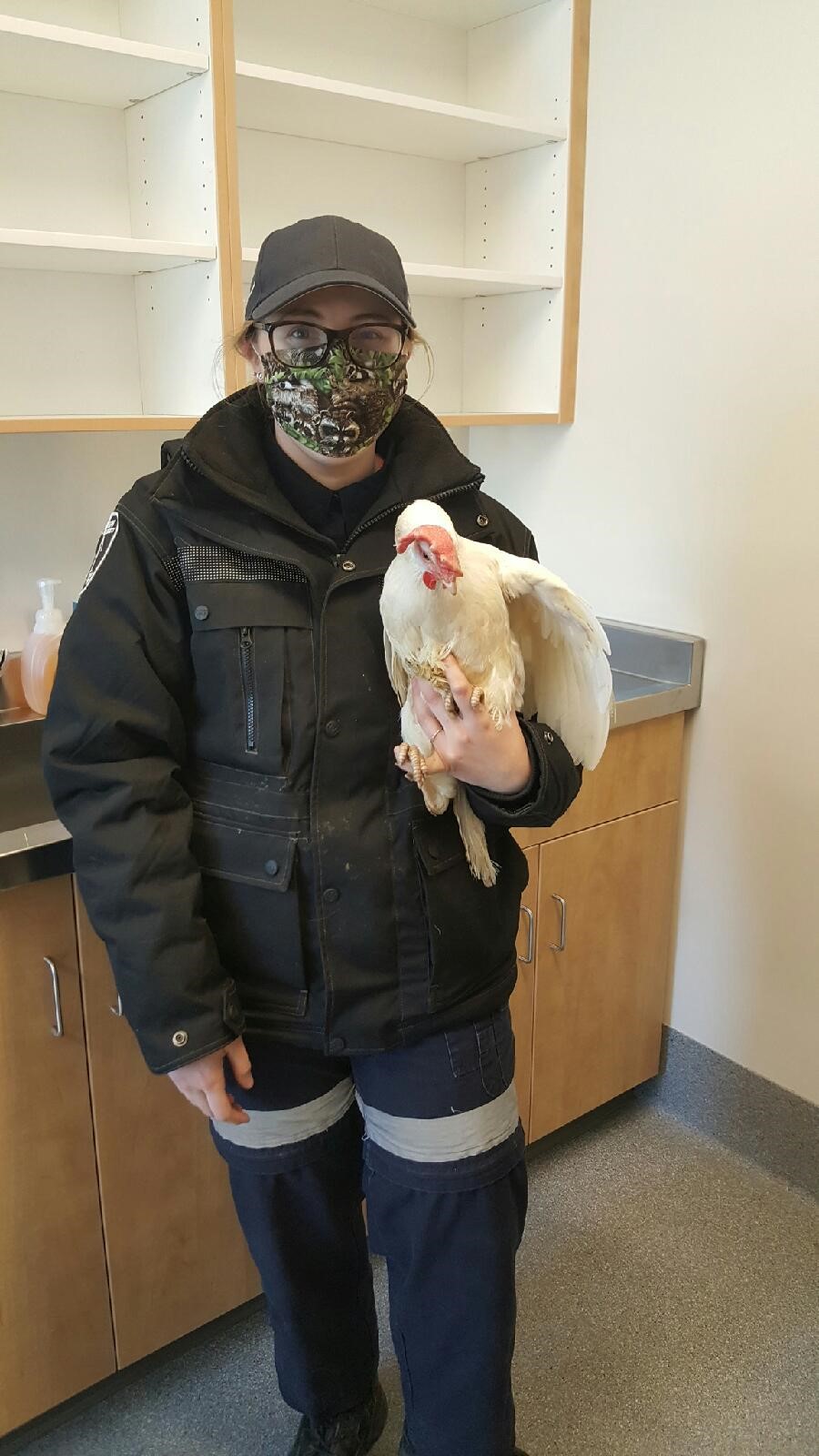 Shannon, wearing a face mask, holding a white rooster
