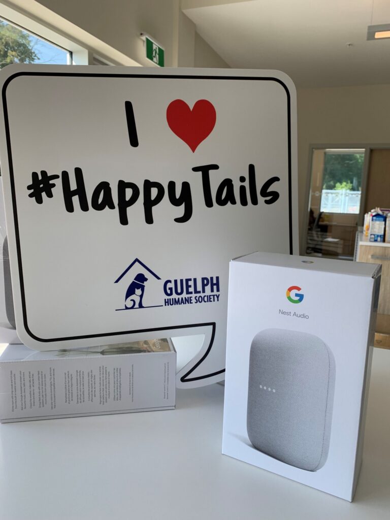 Google Nest speaker box beside a sign that reads "I love #HappyTails" with the Guelph Humane Society logo